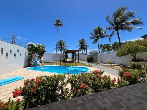 ein Swimmingpool in einem Garten mit Palmen in der Unterkunft Casa vista Mar, pé na areia com piscina ! in Pitimbu + 50 Fotos