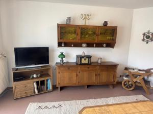 a living room with a tv and a wooden entertainment center at LandgasthofOrleshausen in Büdingen
