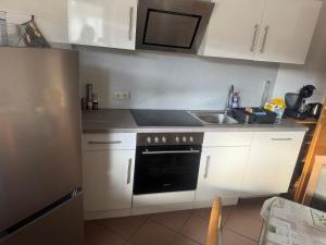 a kitchen with white cabinets and a sink and a stove at LandgasthofOrleshausen in Büdingen +4 photos