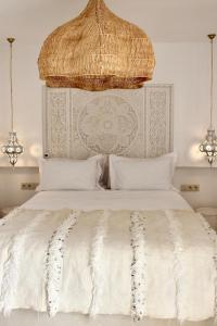 a white bed with a large headboard and white pillows at Riad de charme privatisé au cœur de la médina in Oulad Akkou