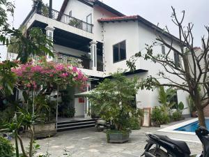 a white house with a swimming pool and flowers at BamBoo Villa Homestay in Ninh Binh
