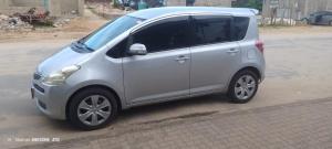 um pequeno carro prateado estacionado ao lado de uma rua em Izaque Taxi e Viagens em Vila Praia do Bilene