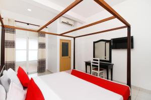 Schlafzimmer mit einem roten Bett und einem Schreibtisch in der Unterkunft Royal Oshin Hotel in Wadduwa