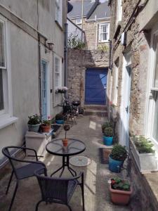 an alley with a table and chairs and potted plants at 2 Courtyard Mews in Penzance