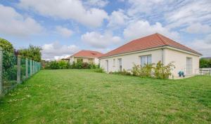 a white house with a fence and a yard at Le Fairway in Bréviandes