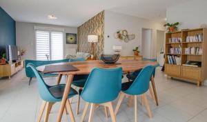 a dining room with a wooden table and blue chairs at Le Fairway in Bréviandes
