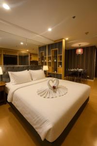 a bedroom with a large white bed with a flower on it at Modern Suite near BTS Nana Netflix Sky View in Makkasan