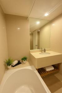 a bathroom with a tub and a sink and a mirror at Modern Suite near BTS Nana Netflix Sky View in Makkasan +4 photos