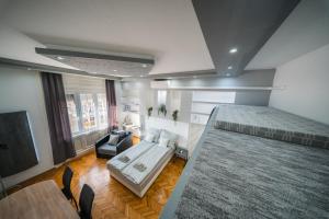 een slaapkamer met een bed, een bank en een tv bij Széchenyi Apartman (III. Panorama) Miskolc belvárosában in Miskolc