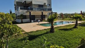 ein Haus mit einem Swimmingpool davor in der Unterkunft Villa confort in Oulad Tayeb