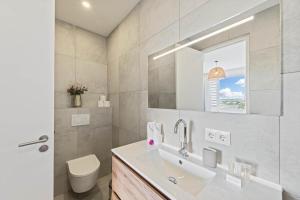 a bathroom with a sink and a toilet and a window at Coral Whisper - Aquamarine 8 in Willemstad