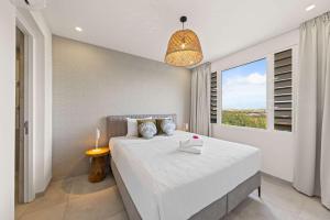 a bedroom with a large white bed and a window at Coral Whisper - Aquamarine 8 in Willemstad