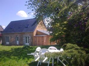 a house with white lawn chairs in the yard at Gîte La Poterie in Jupilles