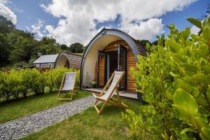 a tiny house with two chairs in front of it at Polgooth Inn in St Austell