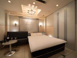 a bedroom with a bed and a couch and a chandelier at ホテルレジェンドプラス-Adult only in Kyoto