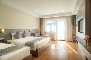 a hotel room with two beds and a window at Orbit Hotel Nha Trang in Nha Trang