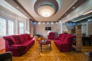 ein Wohnzimmer mit zwei roten Stühlen und einem Tisch in der Unterkunft Széchenyi Apartman (IV Deluxe) Miskolc belvárosában in Miskolc