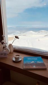 a book and a cup of coffee on a window sill at Kaf Mount Erciyes in Hacılar