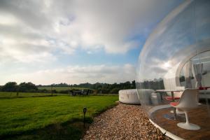 a glass igloo with a table and chairs in a field at Barn bubble in Maidstone