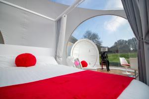 a bedroom with a red bed and a large window at Barn bubble in Maidstone