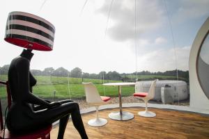 a woman sitting in a chair next to a table with a lamp at Barn bubble in Maidstone