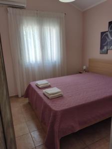 een slaapkamer met een paars bed met 2 handdoeken erop bij Rias Efthimiou House in Kanallákion