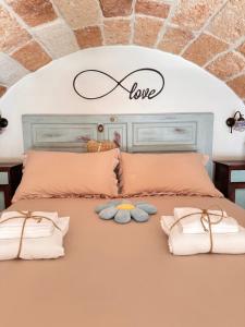 een bed met twee kussens en een bord dat liefde leest bij B&B Casa Fiore in Polignano a Mare