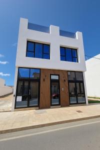 un edificio bianco con finestre nere su una strada di Hoy Cotillo Apartments a Cotillo