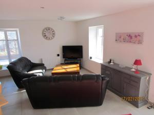 a living room with black leather furniture and a flat screen tv at Gîte Du Maroye in Montreuil