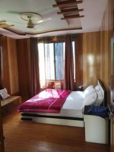 um quarto com uma cama grande com um cobertor vermelho em Flora Inn Skardu em Skardu mais 17 fotografias