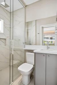 a white bathroom with a toilet and a shower at Cobertura Duplex Vista Mar - Ofurô - 4 suítes in Bombinhas