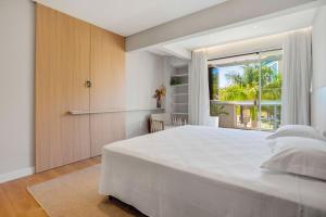 a bedroom with a large white bed and a window at Cobertura Duplex Vista Mar - Ofurô - 4 suítes in Bombinhas