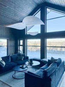 a living room with couches and tables and windows at Mountain Cabin At Hardangervidda in Uvdal