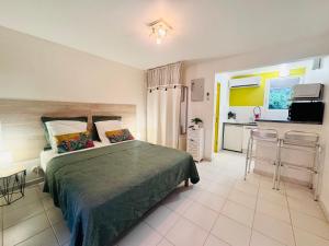 a bedroom with a large bed and a kitchen at Superbe Studio Ultra COSY à 2 min de la PLAGE in Sainte-Anne