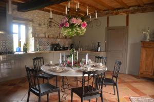 a dining room with a table with chairs and flowers on it at Le Murmure des Fées in Issigeac
