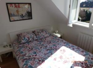um quarto com uma cama com uma colcha floral e uma janela em Bel appartement à 10 minutes du marché de Noël de Strasbourg em Schiltigheim
