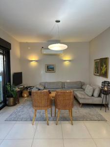 a living room with a couch and a table and chairs at Garden apartment in Ramat HaSharon in Ramat Hash Sharon