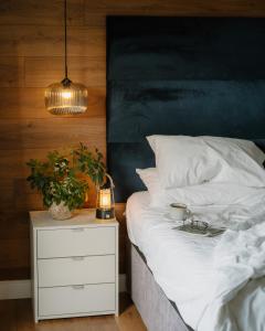 un letto con lenzuola bianche e un comodino con una pianta di Landal Rockingham Forest a Wansford