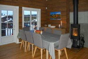 a dining room with a table and chairs and a stove at Log Cabin By Mostertoppen Ski Stadium in Hafjell