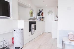 a living room with white walls and a tv at Bovisand Beach Area Chalet, 2-Bed Sea View with Gated Parking & BBQ in Plymouth