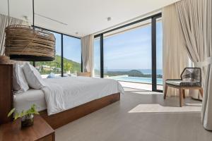 a bedroom with a large bed and a large window at Sea Breeze Villa in Taling Ngam Beach