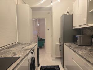 a kitchen with white cabinets and a washer and dryer at Pet Friendly 2 Bed Ground Floor Apartment in Addlestone with Free Driveway Parking in Addlestone