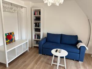ein Wohnzimmer mit einem blauen Sofa und einem Tisch in der Unterkunft Ruhiges und citynahes Dachgeschoss-Nest in Düsseldorf