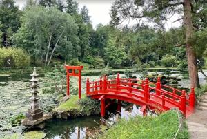 un pont rouge au-dessus d'un étang dans un jardin dans l'établissement Le Petit Héros Gîte, à Courlay