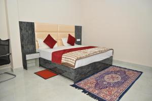 a bedroom with a bed with red pillows and a rug at Hotel Sai Palace in Masodha
