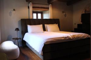 a bedroom with a bed with white sheets and a window at Cascina Manzoni in Bossolasco