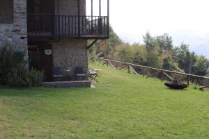 a building with a balcony on top of a grass field at Cascina Manzoni in Bossolasco
