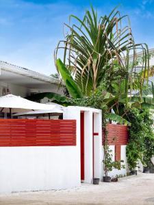 a white and red fence with a palm tree behind it at The Wave Dhigurah in Dhigurah