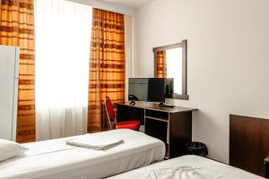 une chambre d'hôtel avec deux lits et un bureau avec une télévision dans l'établissement Hotel Strelitia, à Timişoara