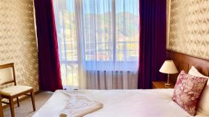 une chambre avec un lit, une fenêtre et une chaise dans l'établissement Хотел Елит Релакс, à Devin 11 autres photos